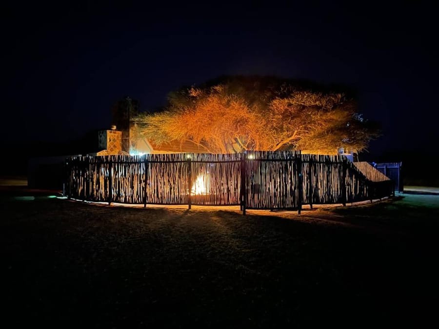 The lodge at night, the boma lit by firelight beneath the trees